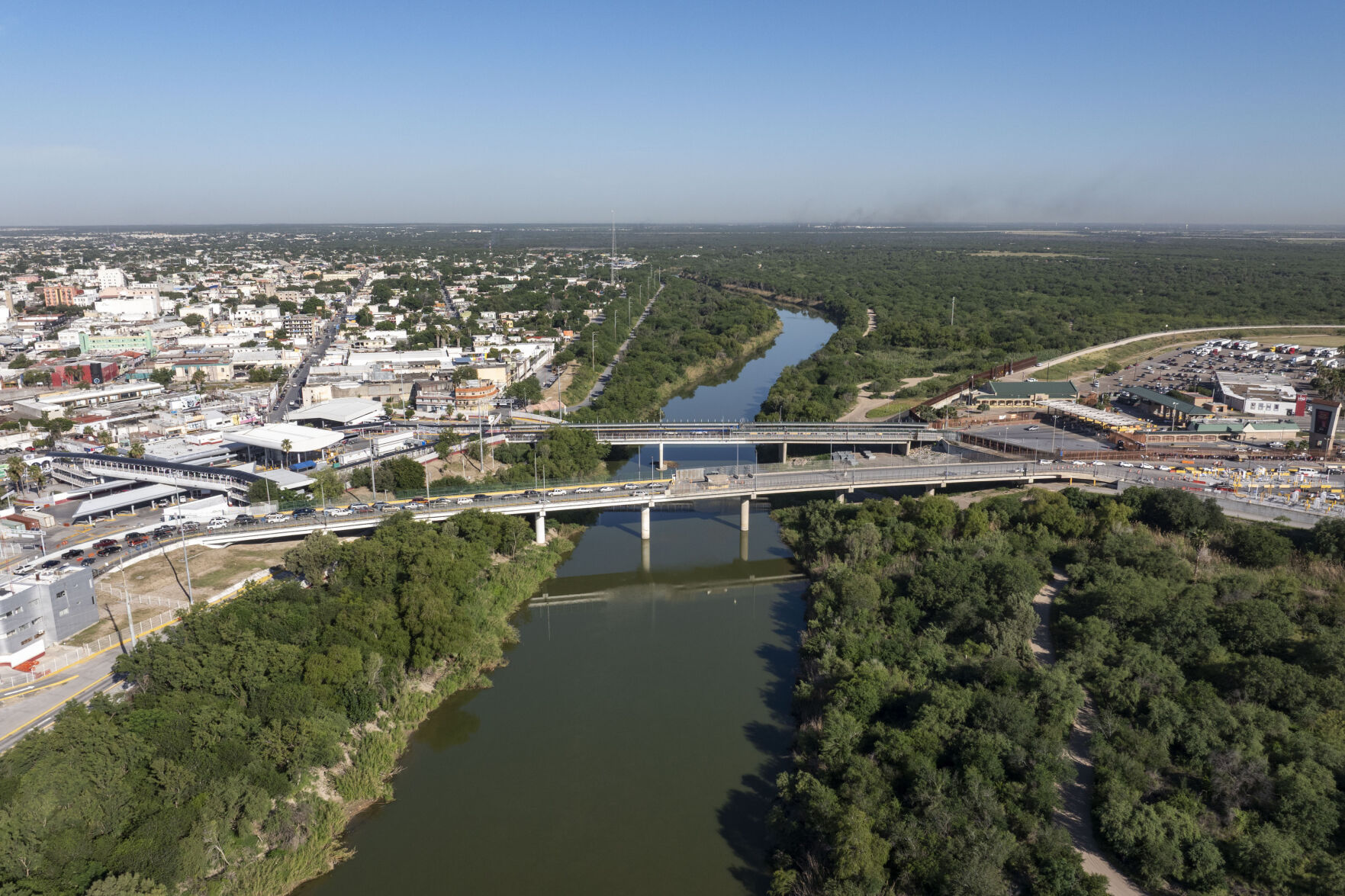 A bridge spans a river with trees and buildings on either side.
